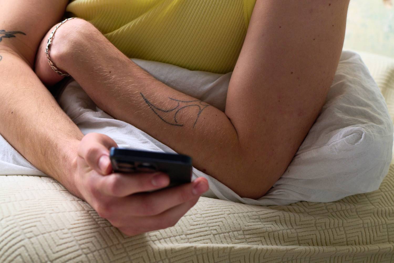 Nahaufnahme einer Person, die im Bett liegt und ein Smartphone hält. Die Szene verdeutlicht die Möglichkeit, den medizinischen Fragebogen zur Behandlung von Erektionsstörungen diskret und bequem von zu Hause aus auszufüllen.