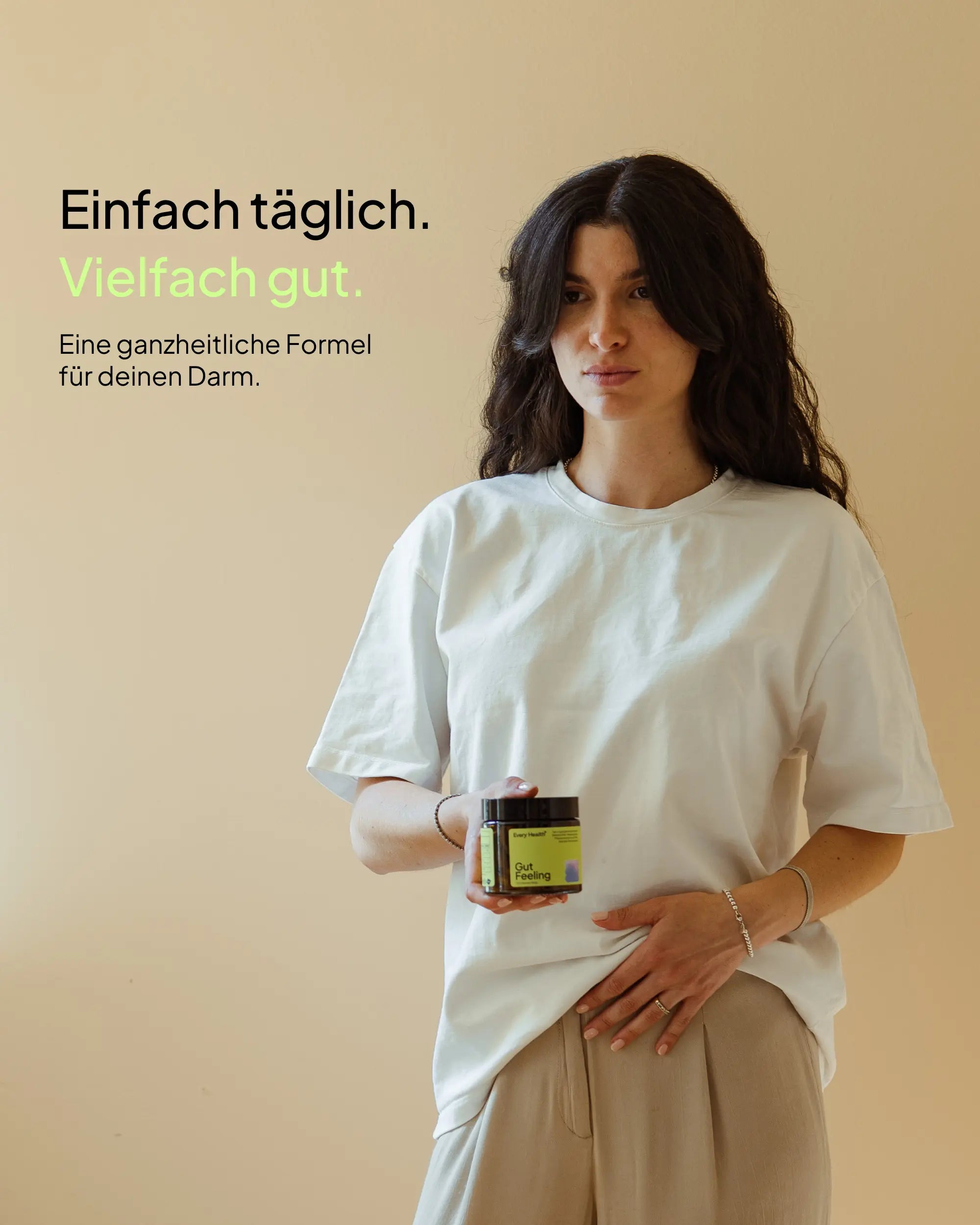 Werbebild von Every Health. Eine Frau mit langen, dunklen Haaren in einem weißen T-Shirt hält eine Dose „Gut Feeling“ Kapseln in der Hand, während ihre andere Hand leicht auf ihrem Bauch liegt. Oben links steht der Text: „Einfach täglich. Vielfach gut. Eine ganzheitliche Formel für deinen Darm.“