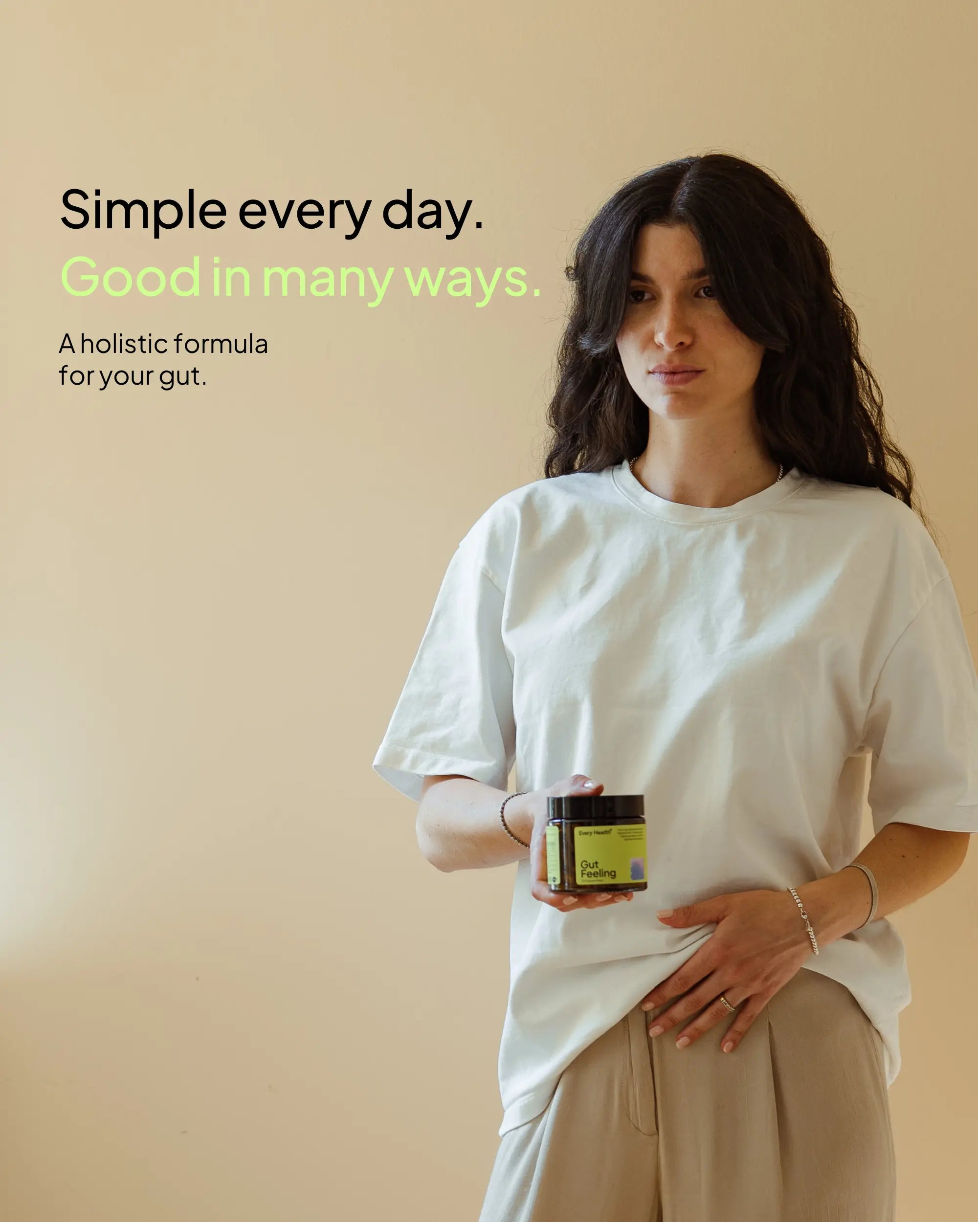 A woman with long dark hair, wearing a white t-shirt and beige trousers, stands against a warm background holding a jar of "Every Health Gut Feeling" supplements in one hand while placing their other hand on her stomach. The text on the left reads: "Simple every day. Good in many ways. A holistic formula for your gut."