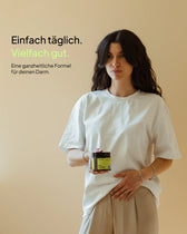 Werbebild von Every Health. Eine Frau mit langen, dunklen Haaren in einem weißen T-Shirt hält eine Dose „Gut Feeling“ Kapseln in der Hand, während ihre andere Hand leicht auf ihrem Bauch liegt. Oben links steht der Text: „Einfach täglich. Vielfach gut. Eine ganzheitliche Formel für deinen Darm.“